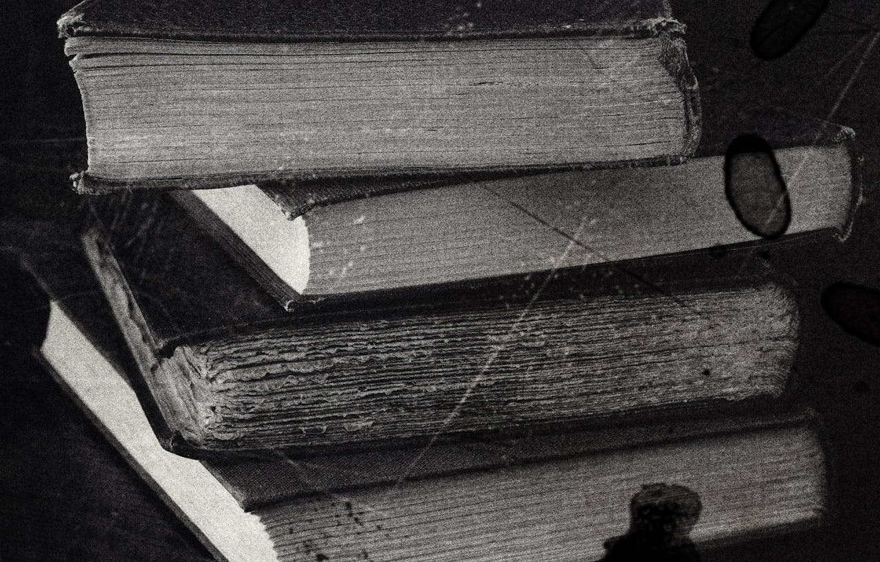 about-02 Close-up of a stack of vintage books in black and white, showcasing the texture of old paper.